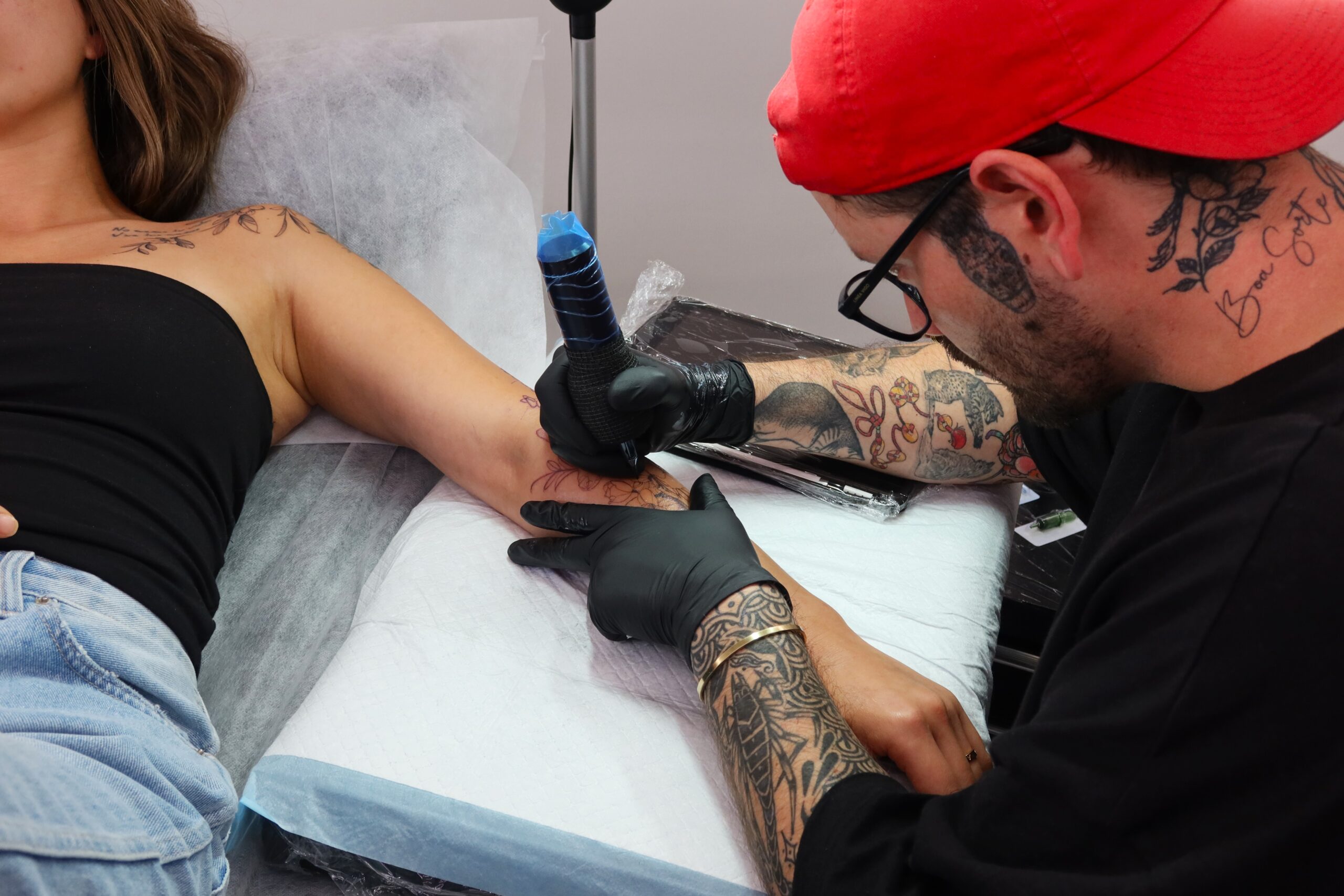 Tattoo artist applying tattoo to a woman's arm